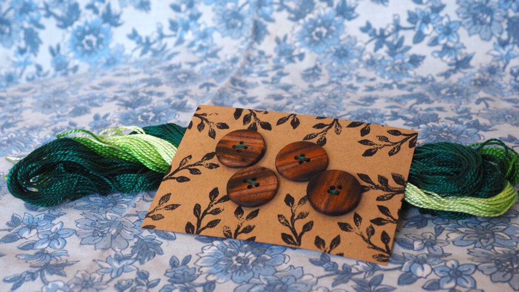 Des boutons en bois sur une petite carte en craft. Les boutons sont fait d'un bois plein de couleurs très différentes