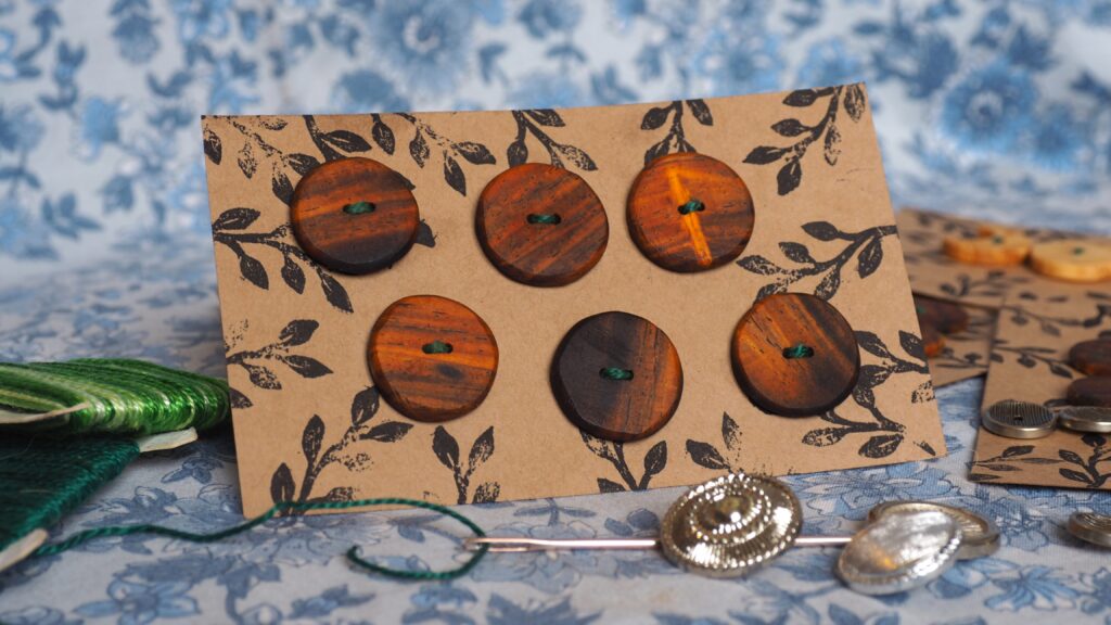 Une photo en gros plan d'une plaque de boutons. Il y a 6 boutons aux couleurs intenses, allant d'un orange clair assez vif à du marron sombre, tirant sur le noir