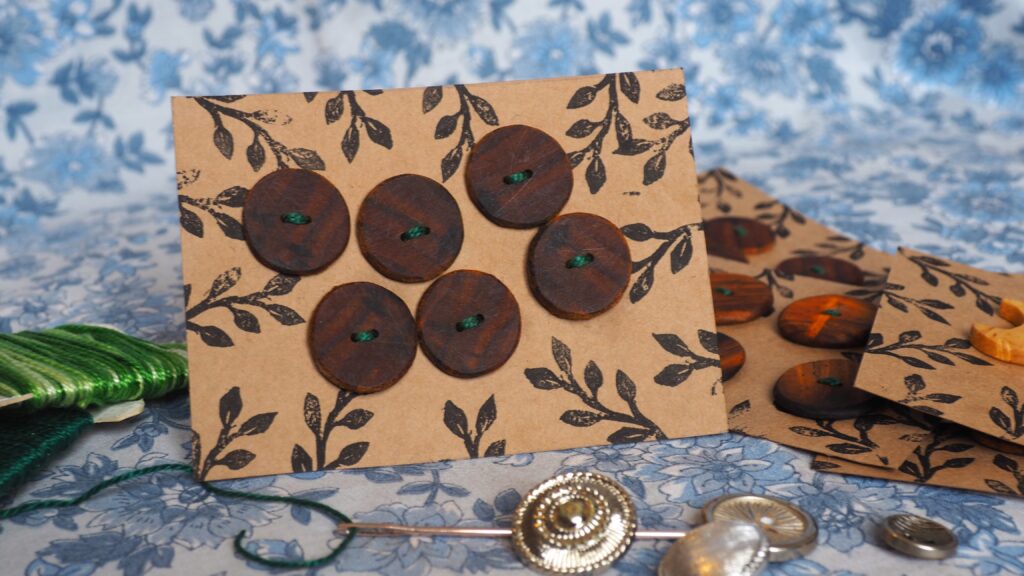 Une photo en gros plan d'une plaque de boutons. Il y a 6 boutons d'un marron sombre, couleur chocolat.